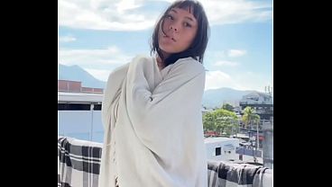 Linda amadora mostrando seios naturais na varanda ao ar livre